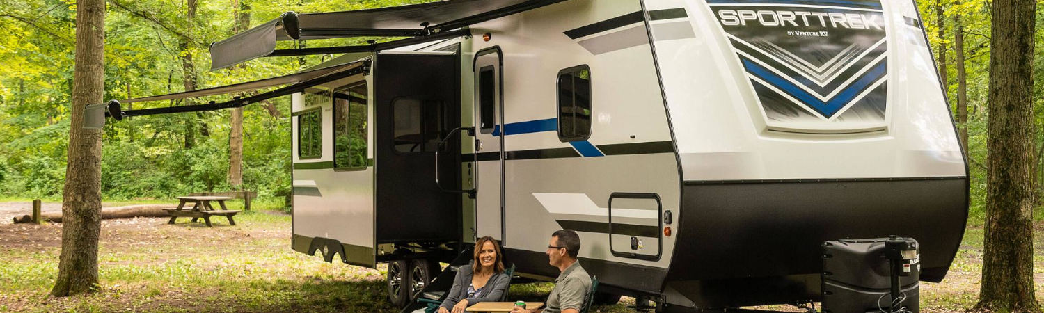 2020 Venture RV SportTrek Lightweight Travel Trailer parked at a campsite with the overhang …